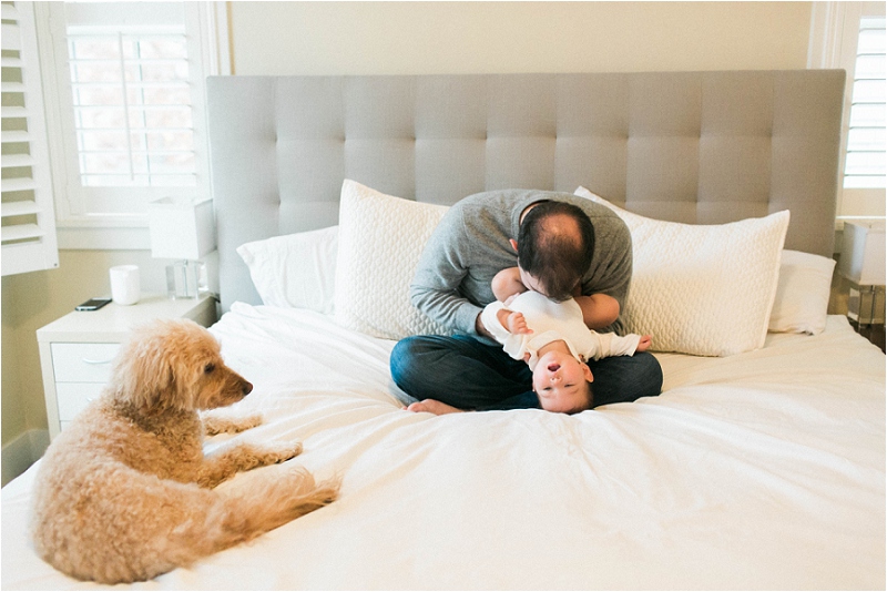 dad kissing baby on bed