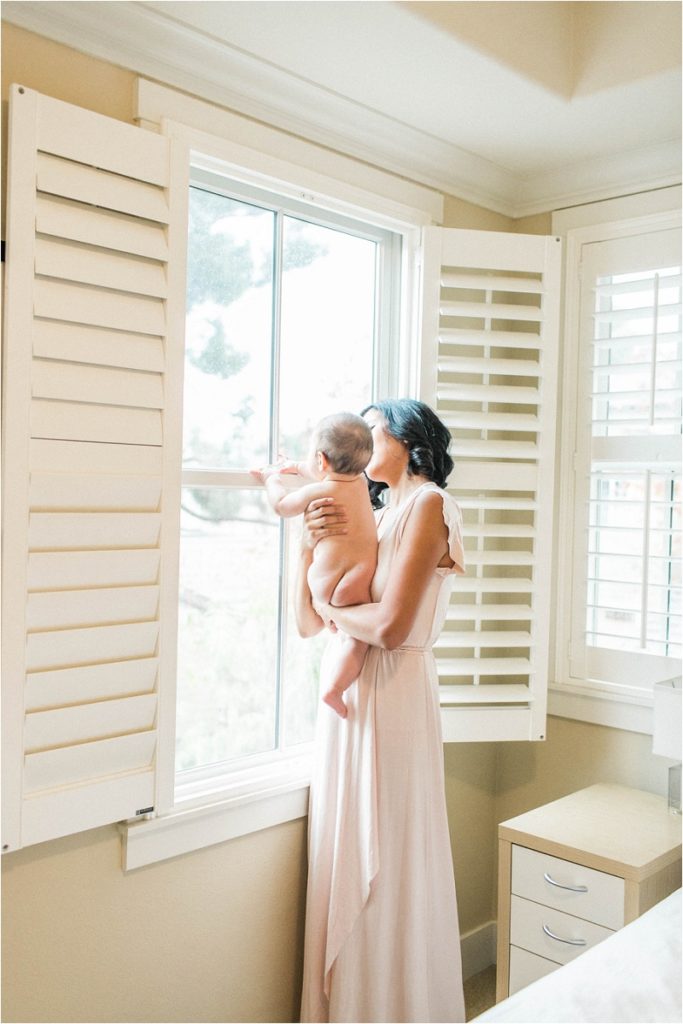 mom holding naked baby looking out window