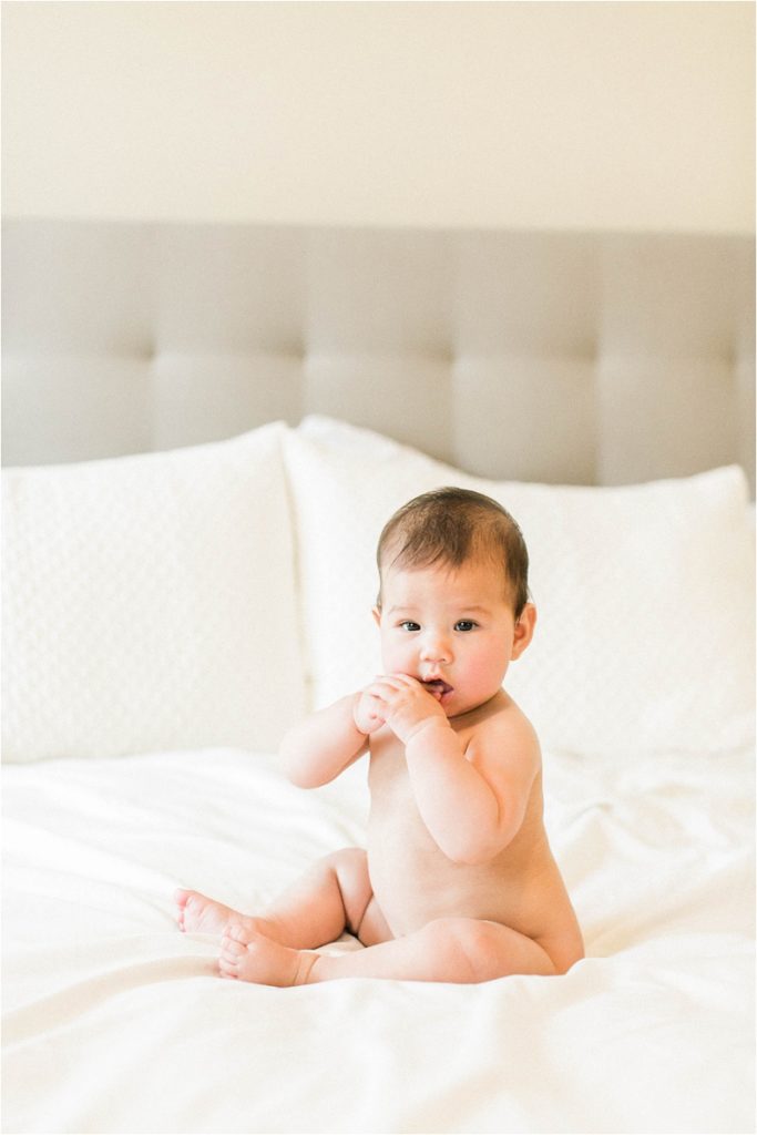 naked baby sittingon bed