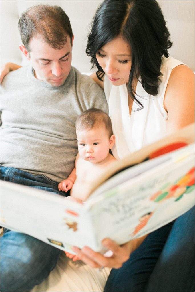 baby looking at book with mom and dad