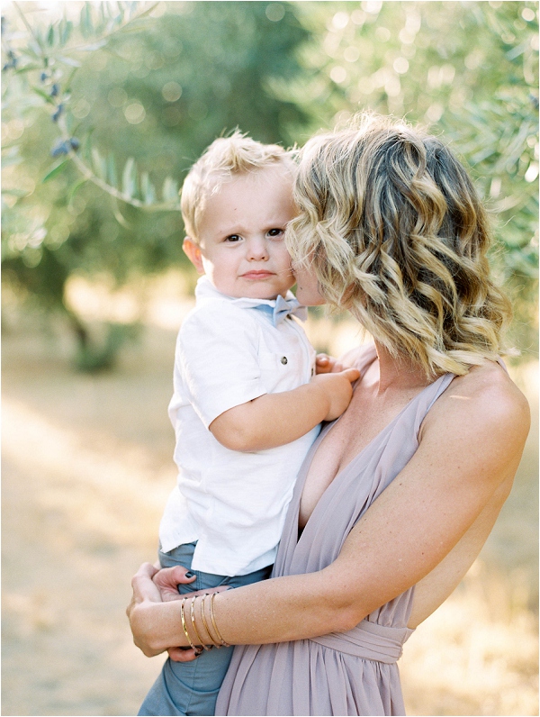 little boy with blue bowtie getting kisses from mommy