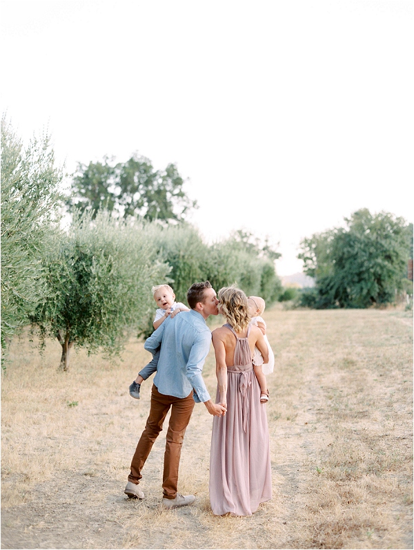 parents kissing in olive orchard holding kids