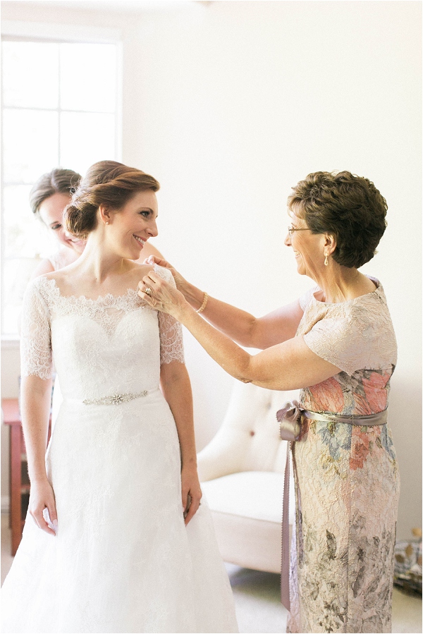 mom helping bride into wedding dress