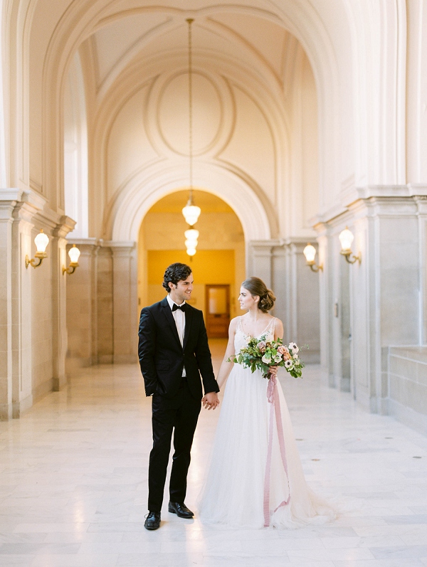 bride and groom holding hands in san francisco city hall