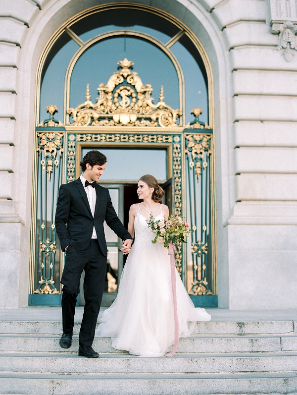 bride and grom holding hands while exiting san francisco city hall