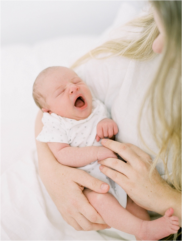 newborn baby yawning in mom's arms