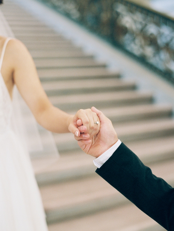 grrom holding hands on the staircase at San Francisco city hall for wedding