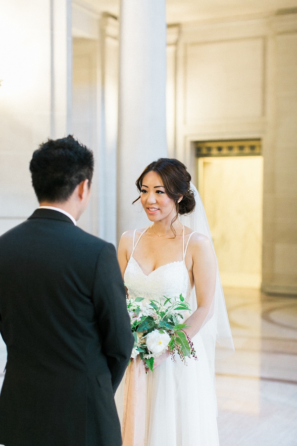 bride looking at groom during wedding at the fourth floor gallery in San Francisco city hall