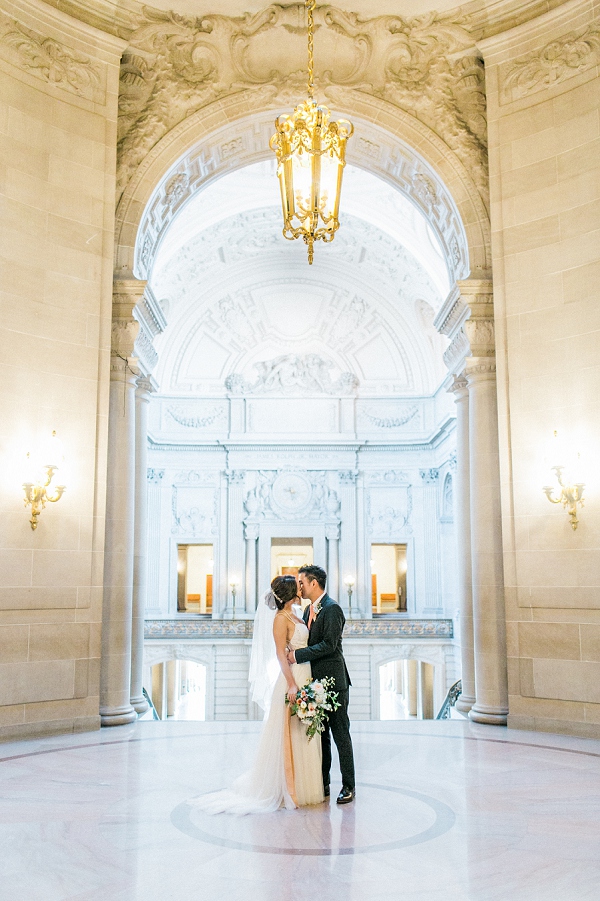 couple kissing under the archway in San Francisco city hall