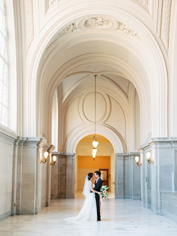 couple hugging under archway inside of San Francisco city hall