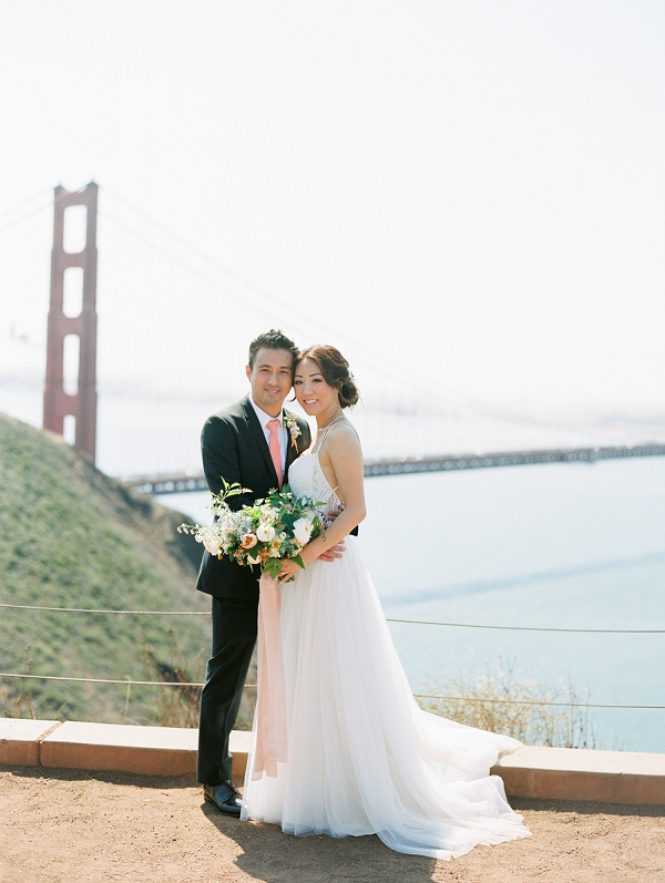 couple cuddling Golden Gate Bridge behind them