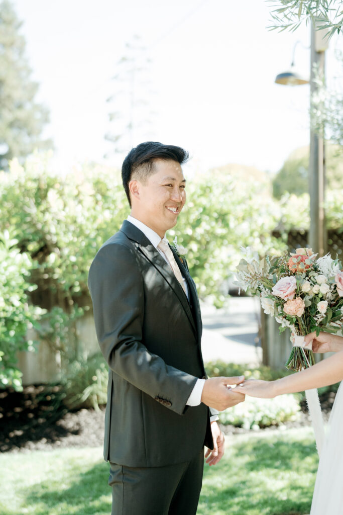 Grooms smiling as he sees bride for the first time, holding brides hands. Tres Posti Napa Valley Wedding