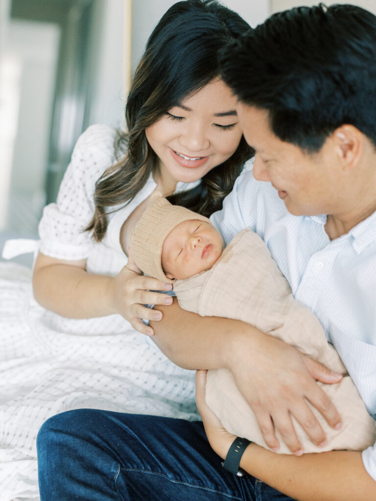 mother and father smiling and holding newborn in bay area newborn session