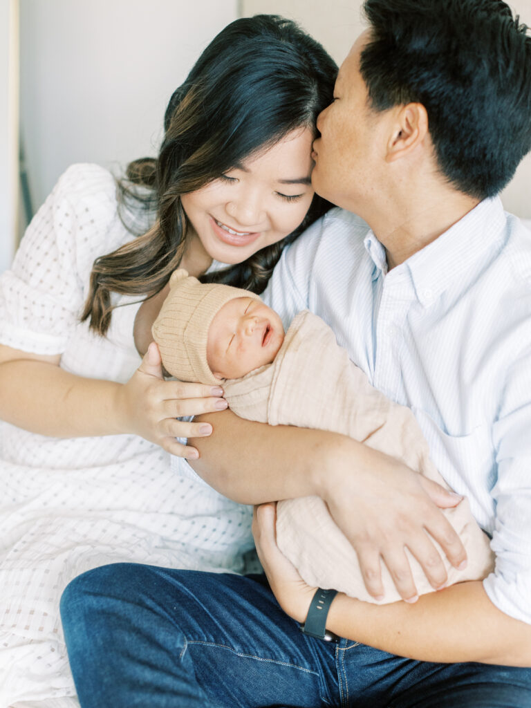 palo alto newborn photography session with husband kssing wife and holding newborn baby