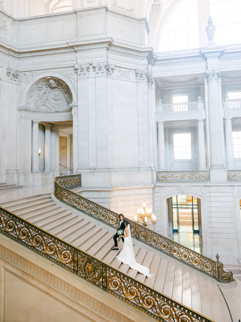 bride and groom walking up grand staircase at San Francisco City Hall
