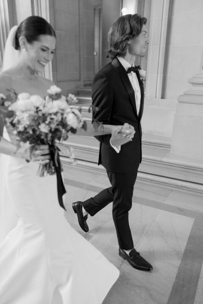 bride and groom holding hands walking in black and white