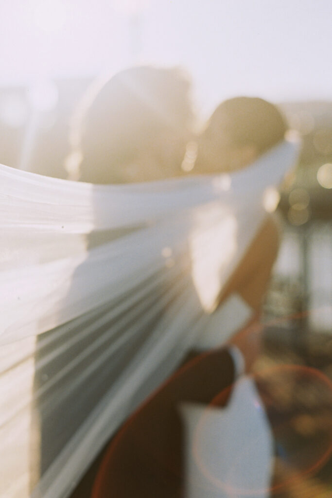 bride and groom kissing with veil flying in front of their faces