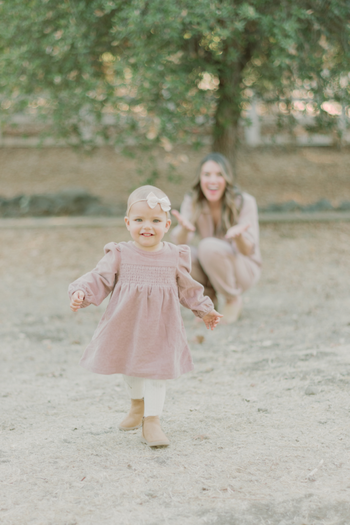 daughter running towards camera and mother smiling in background
