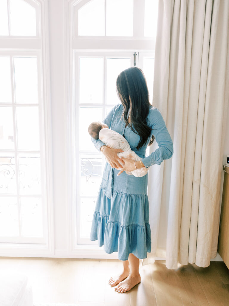 Bay Area Lifestyle Newborn Session.  Mother cradling baby in front of the window.