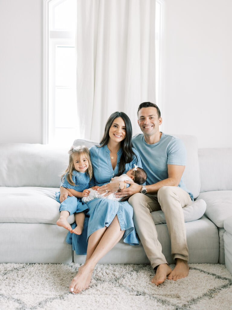 Bay Area Newborn Lifestyle Session.  Family, father, mother, sister, and newborn sitting on the couch