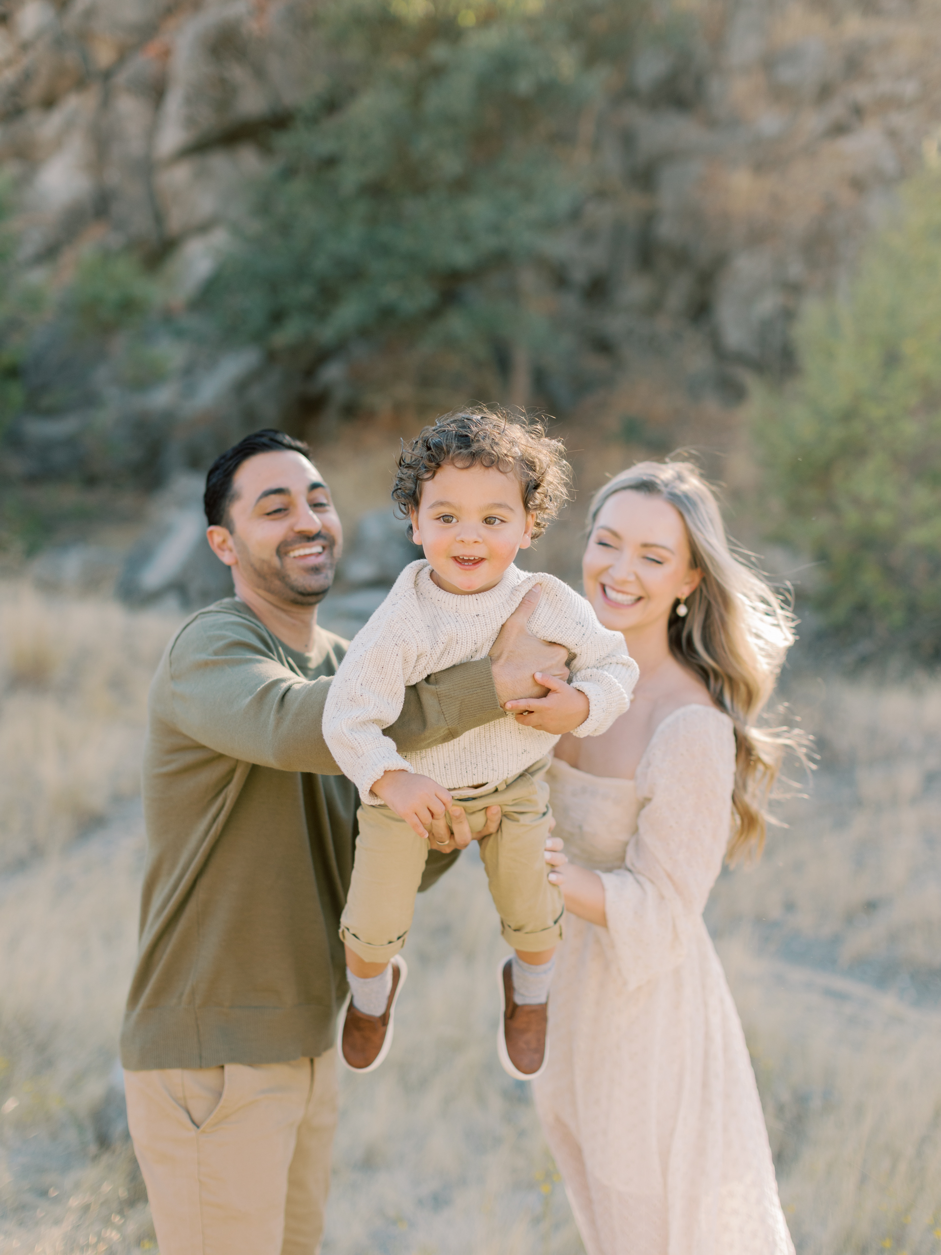Parents cuddling with their toddler during a sunset family session in the Walnut Creek hills, with a natural outdoor style similar to family photos in Marin.